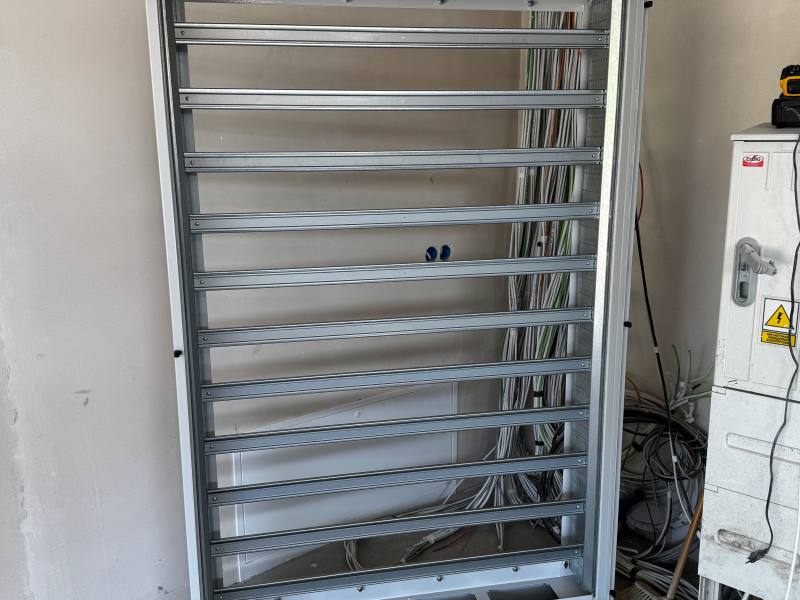 Rama montażowa rozdzielnicy na tle ściany z wiązkami przewodów instalacji automatyki